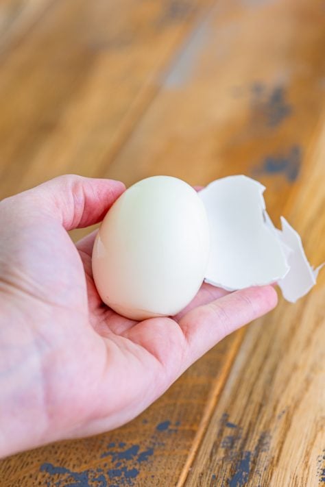 a hand showing the peeling of an egg.