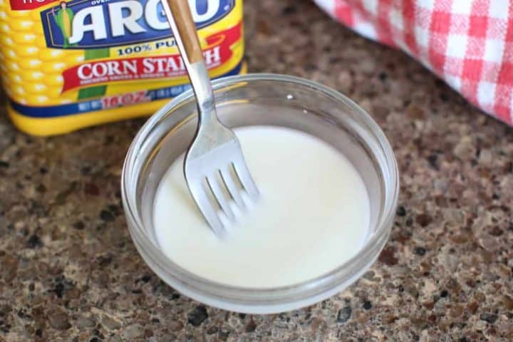 small bowl with a mixture of cornstarch and water being mixed together with a fork.