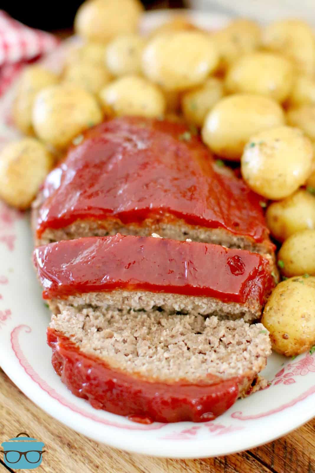 slices of instant pot meatloaf shown surrounded by garlic parmesan baby potatoes on an oval plate.