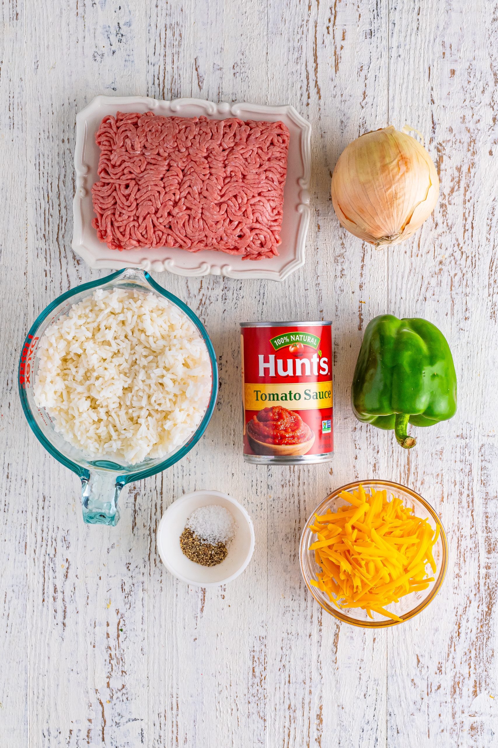 Ground beef, rice, tomato sauce, onion, green bell pepper, salt, pepper, and shredded cheese.