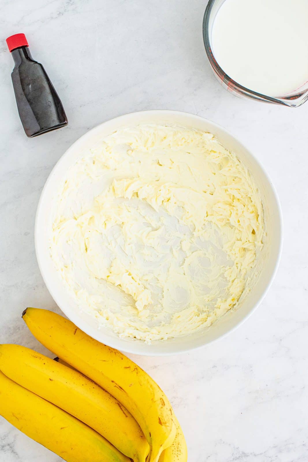 softened cream cheese whipped with an electric mixer in a white bowl.