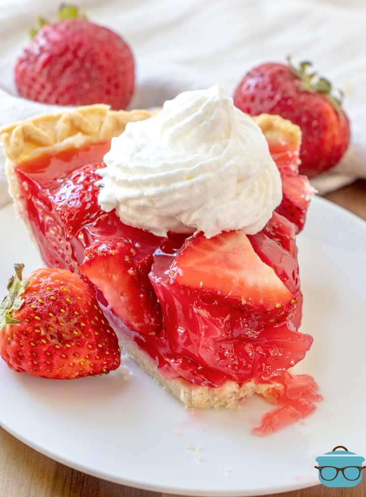 slice of strawberry pie with a bite removed on a round white plate. 