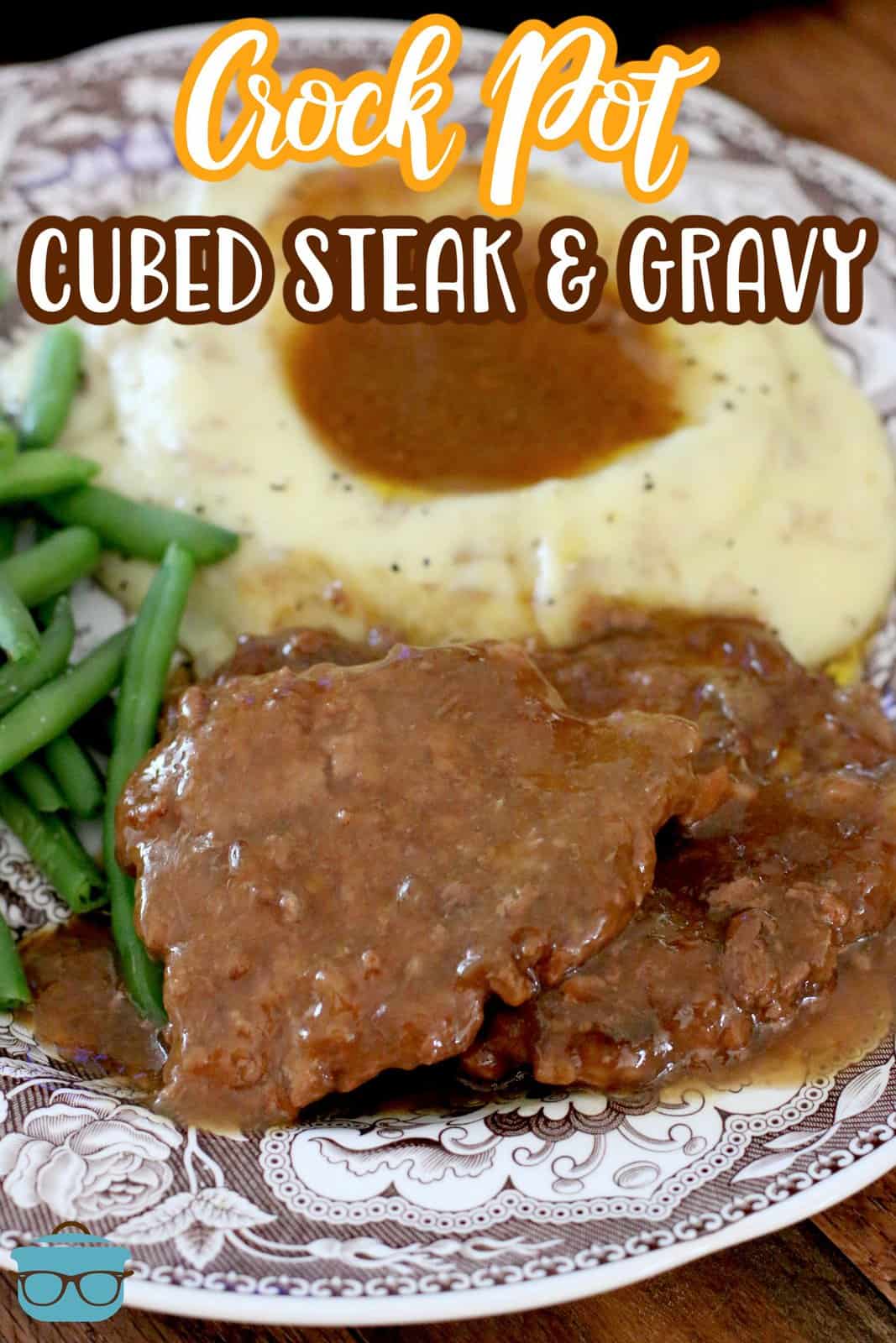 two cubed steaks on a plate with mashed potatoes and green beans.