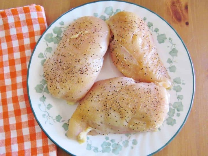 three seasoned chicken breasts on a plate.