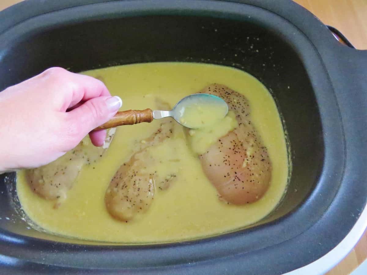 chicken breasts being covered with gravy using a spoon.