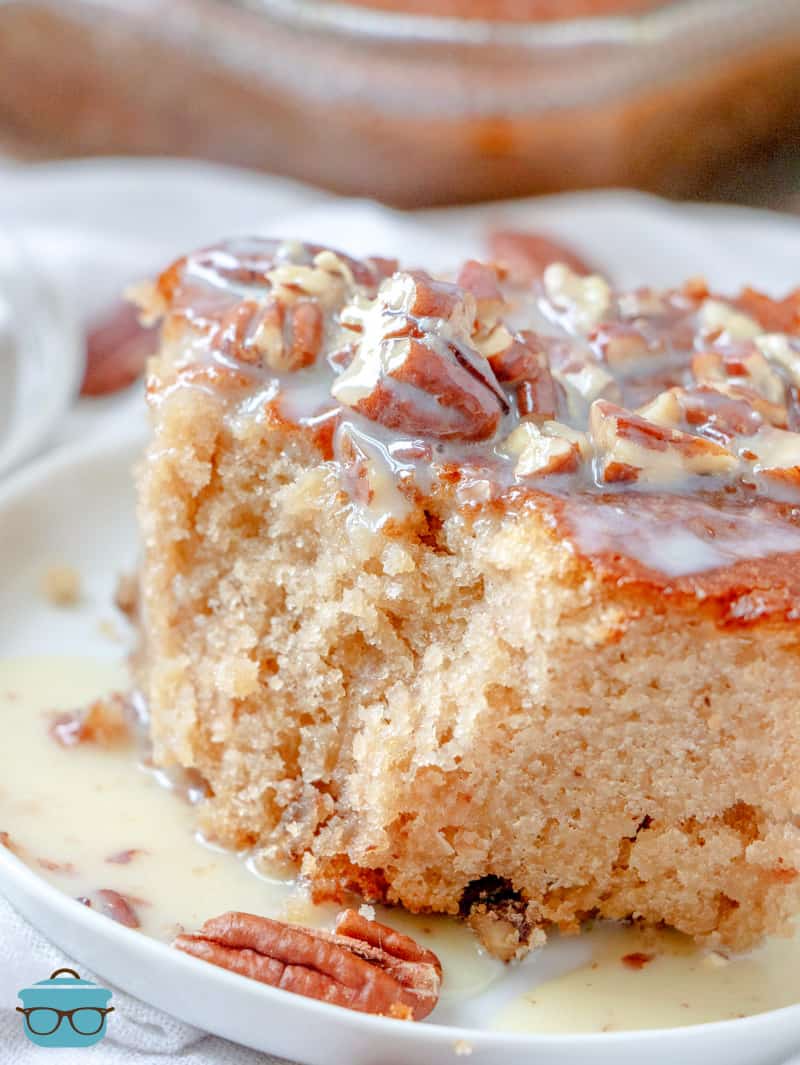 a slice of butter pecan cake shown on a white plate and topped with a butter sauce. 