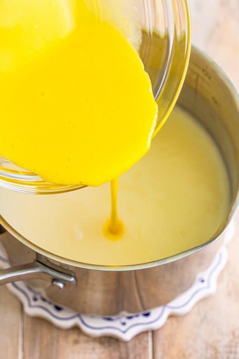 adding egg yolks into sauce pan with milk.