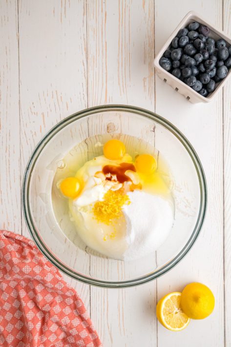 A bowl of yogurt, sugar, eggs, canola oil, lemon zest, and vanilla extract.