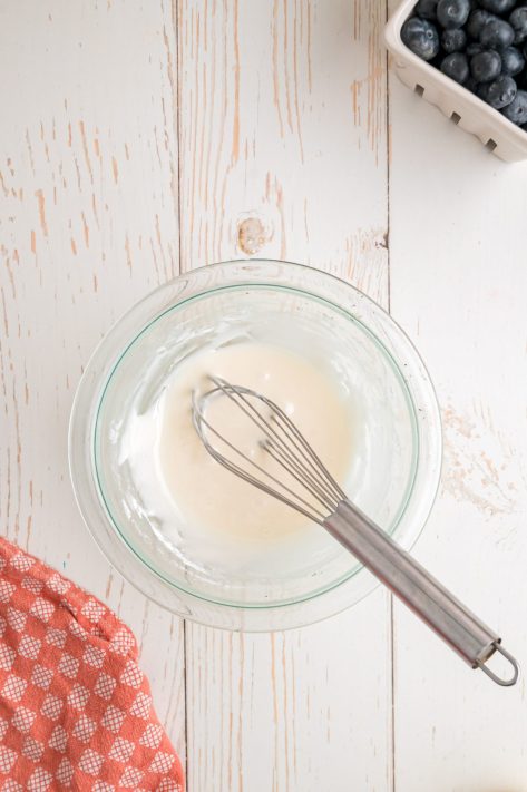 A bowl with powdered sugar, vanilla extract, and milk.