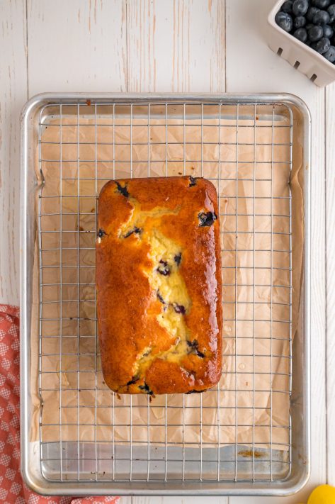 Lemon glaze on a cake cooling on a rack.