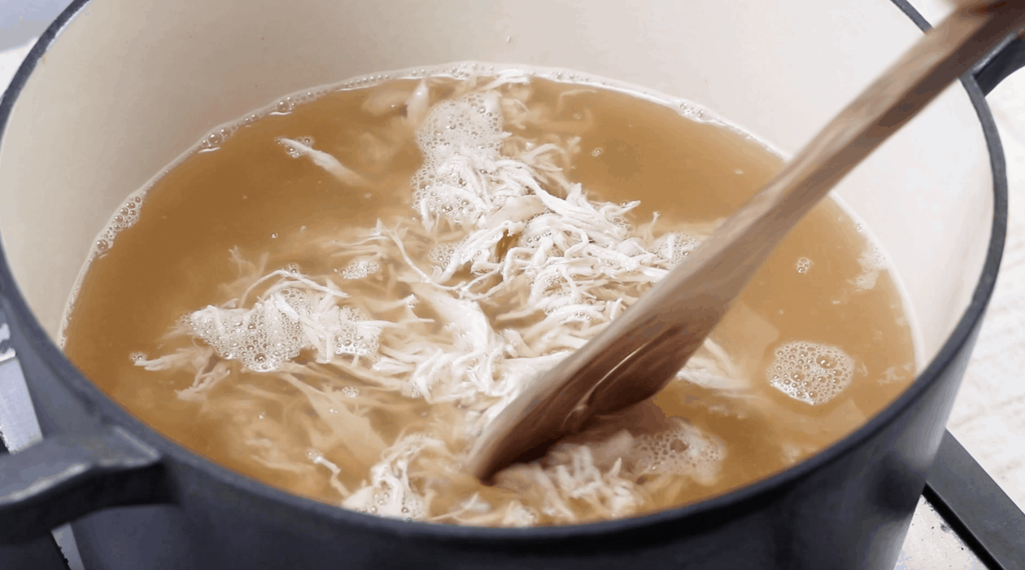 shredded chicken added to chicken broth in a large stock pot