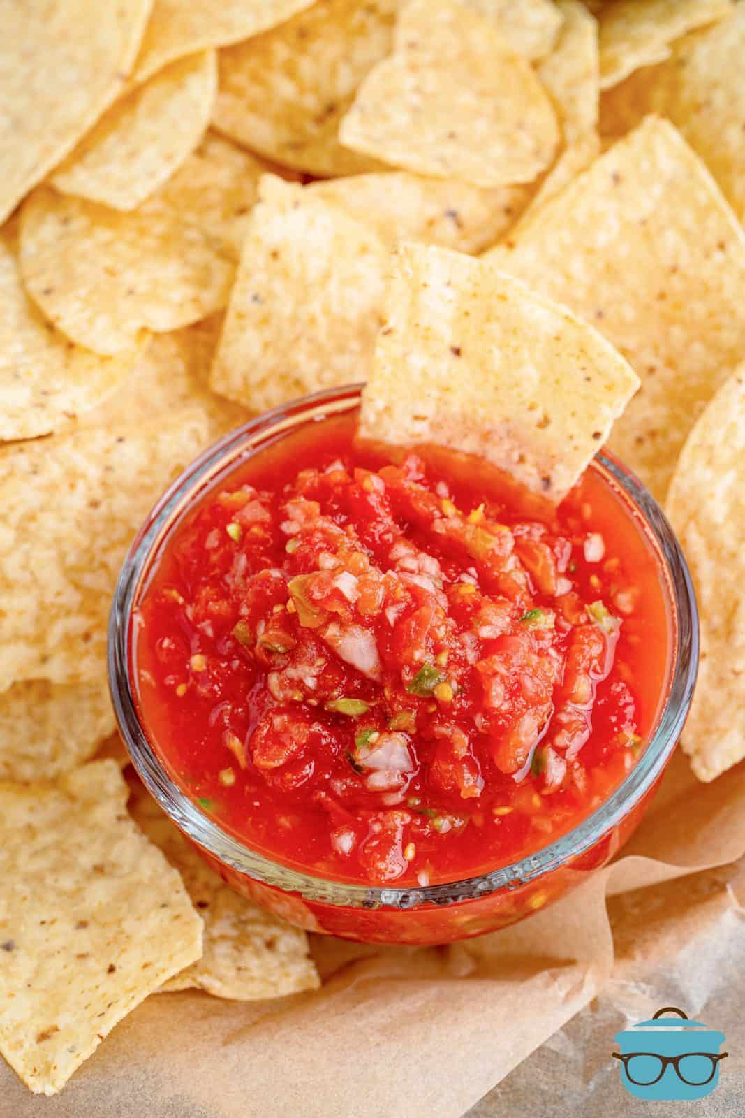 overhead view of salsa in a small bowl surrounded by tortilla chips.