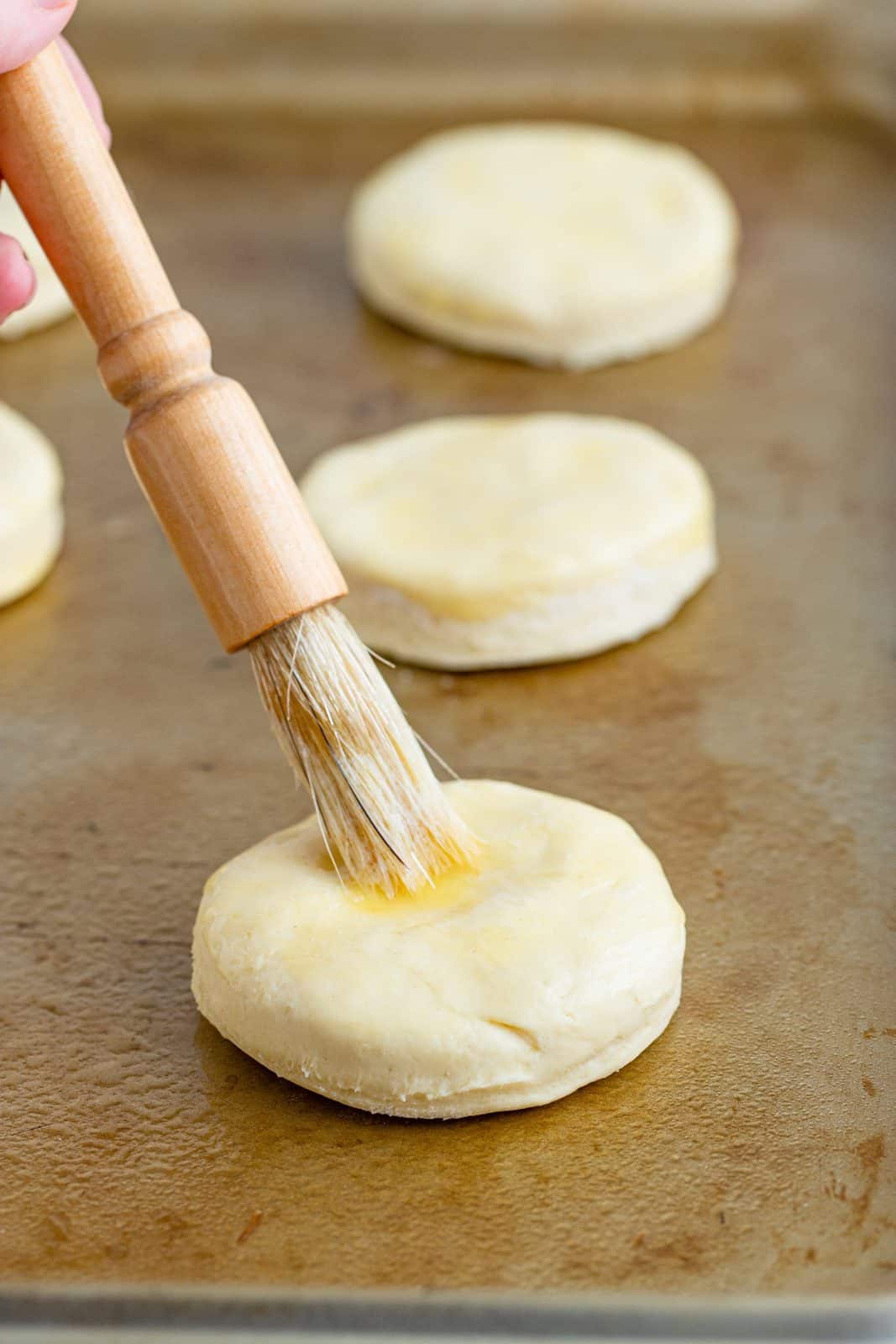 pastry brush shown spreading butter on biscuit dough.
