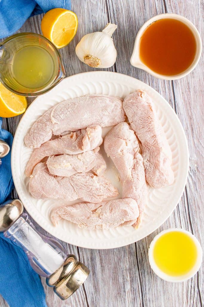 coating chicken breasts in flour in a shallow bowl.