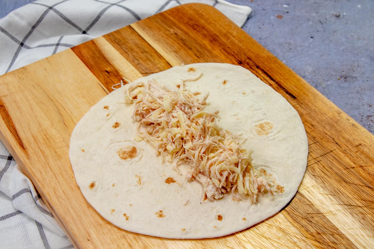 chicken and cheese filling placed into the center of a flour tortilla