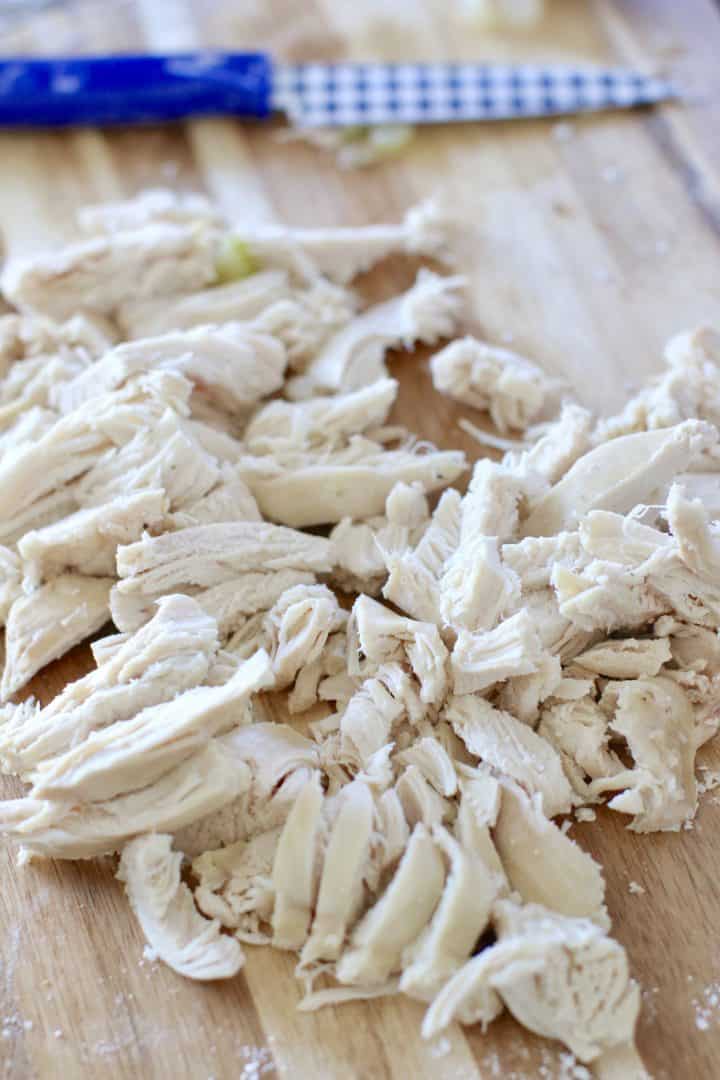 shredded chicken breast meat on a wooden cutting board