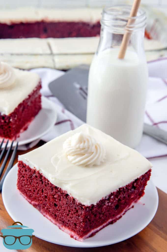slices of red velvet cheesecake cake on small plates with a glass bottle of milk in the background