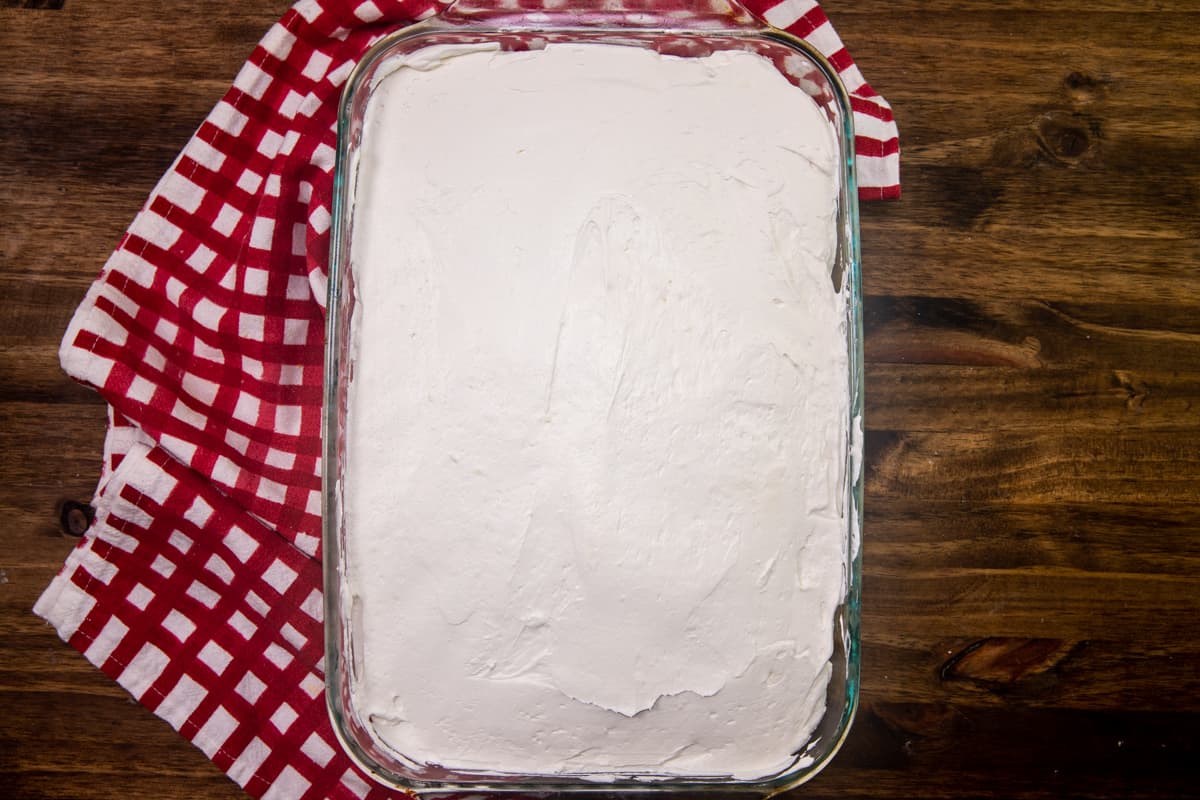 sweetened cream cheese mixture spread evenly onto cooled white cake in baking dish.