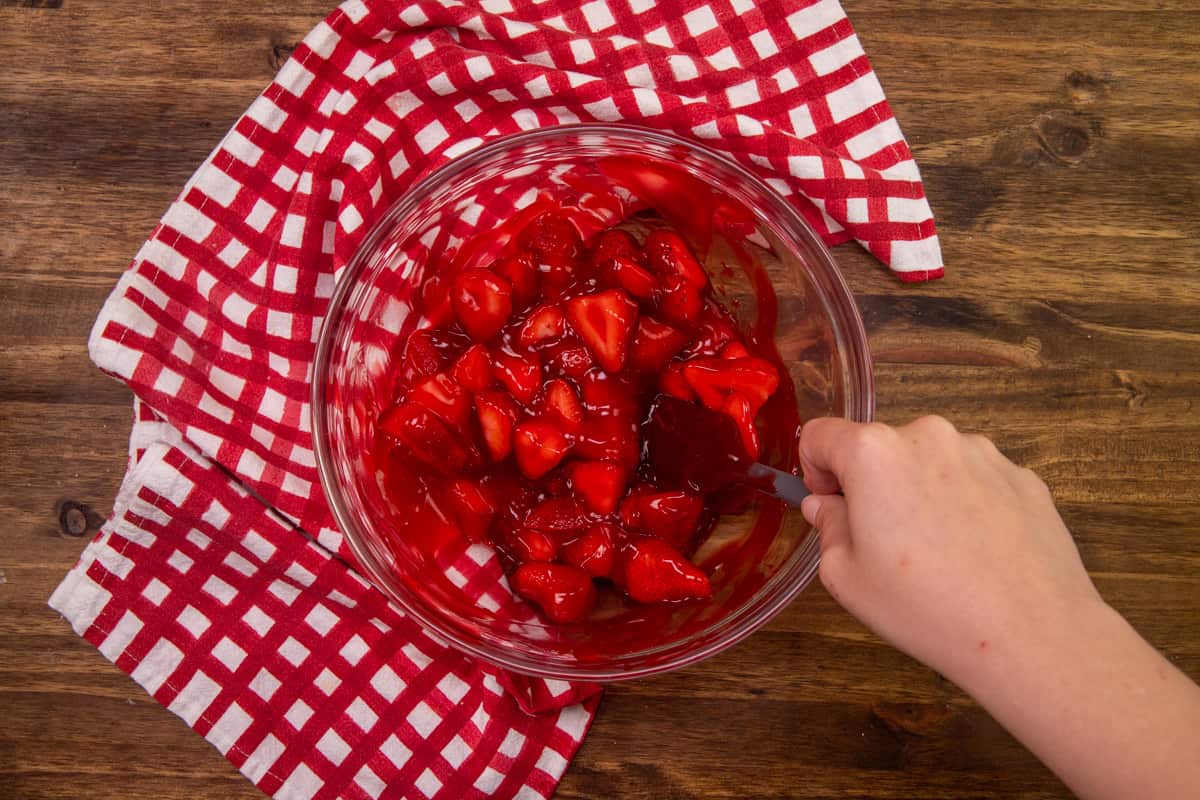 sliced strawberries and strawberry glaze mixed together in a clear bowl.