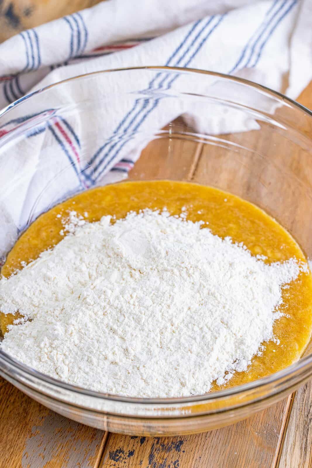flour added to mashed banana mixture in a bowl