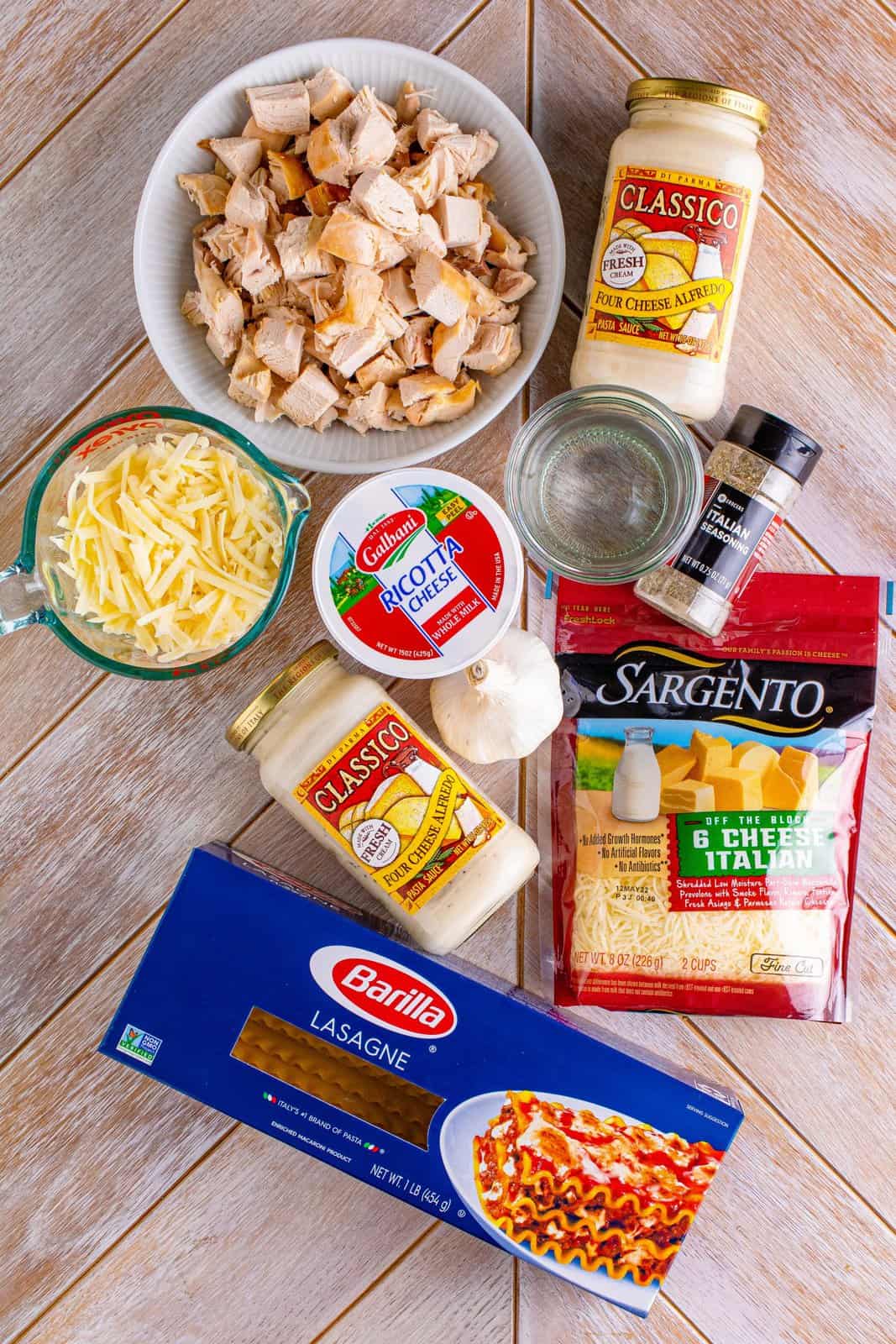 slow cooker, rotisserie chicken, Italian seasoning, Alfredo sauce, lasagna noodles, garlic, ricotta cheese, mozarella cheese.