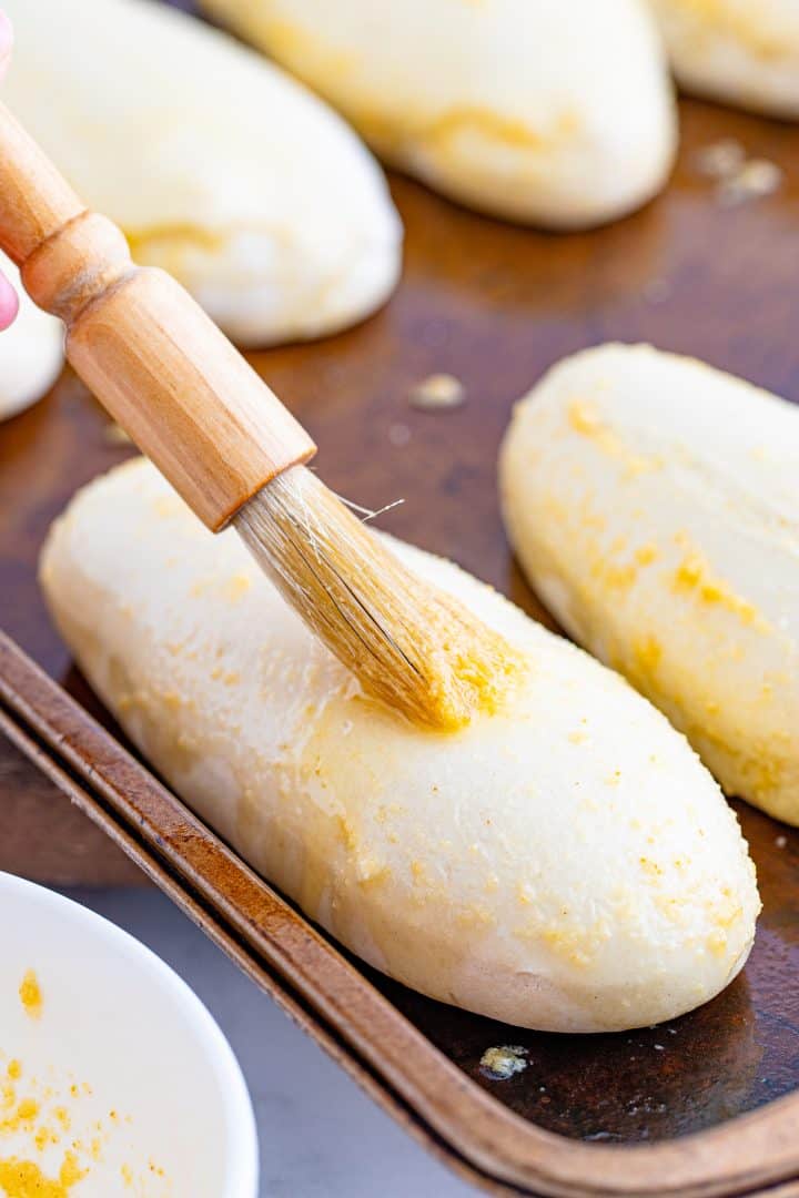brushing breadsticks with garlic butter mixture using a pastry brush. 