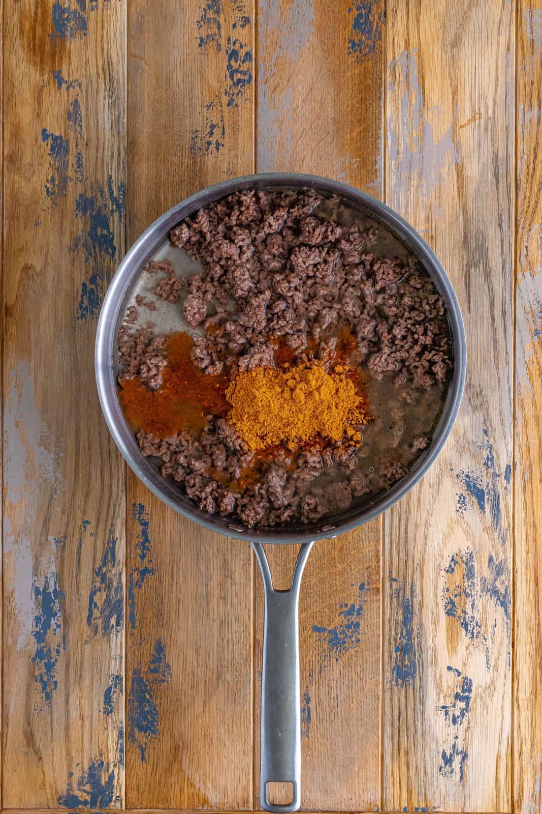 water and taco seasoning  added to cooked ground beef in a skillet.