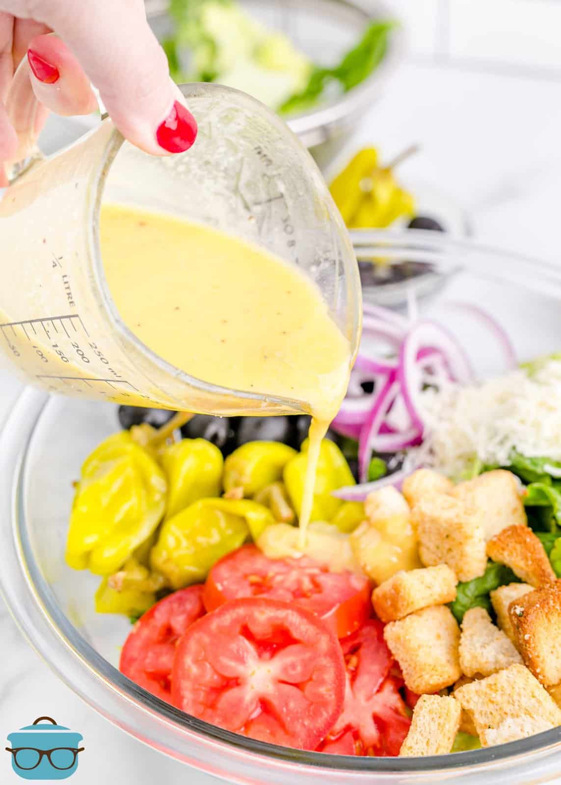 pouring Olive Garden Salad dressing over a salad in a bowl. 