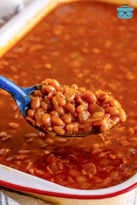 A serving utensil holding a scoop of Southern Baked beans.
