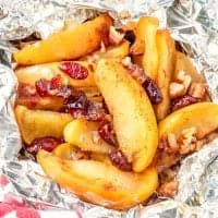 Sliced apples, cranberries, brown sugar, and pecans cooked in aluminum foil