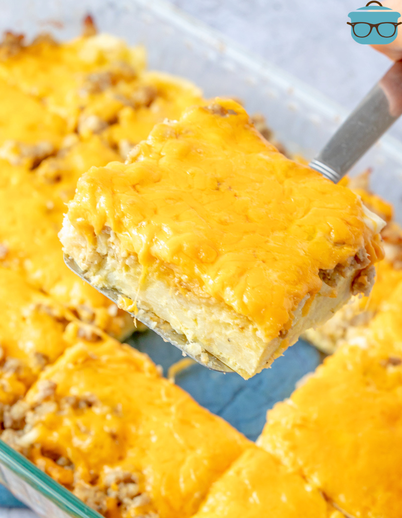 a spatula removing a slice of breakfast hash brown casserole from the baking dish. 