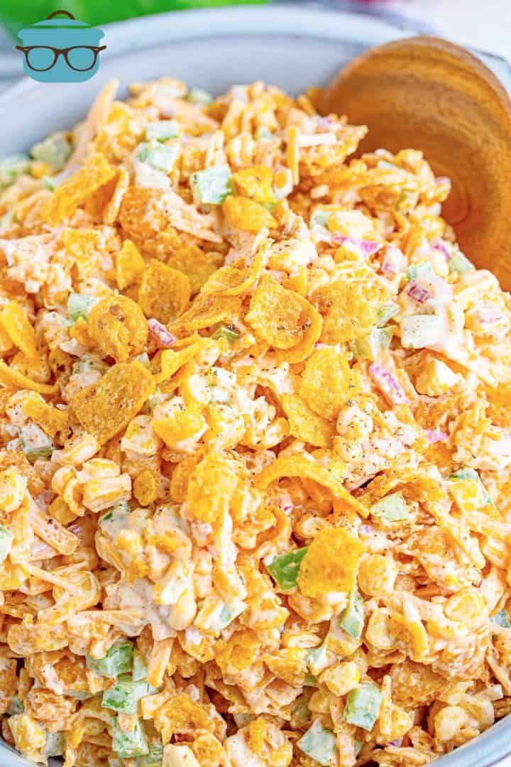 closeup photo of frito corn salad in a bowl with a wooden spoon on the side