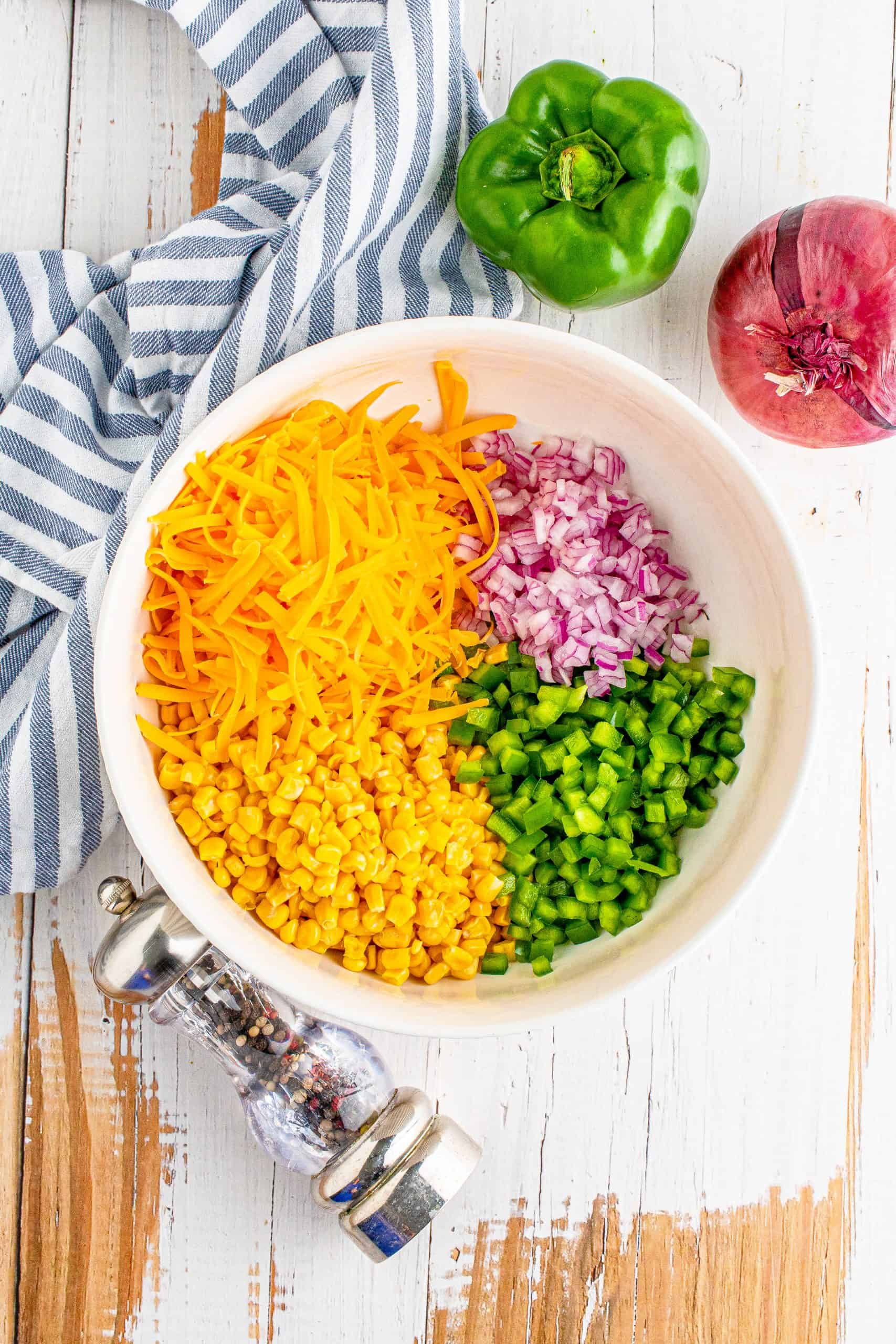 frozen corn, diced green peppers, diced red onion, shredded cheese in a bowl