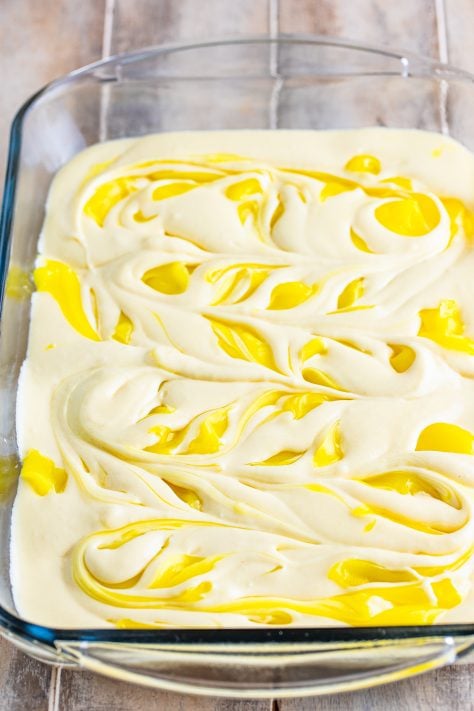 Cake mix swirled with lemon pie filling in a baking dish.