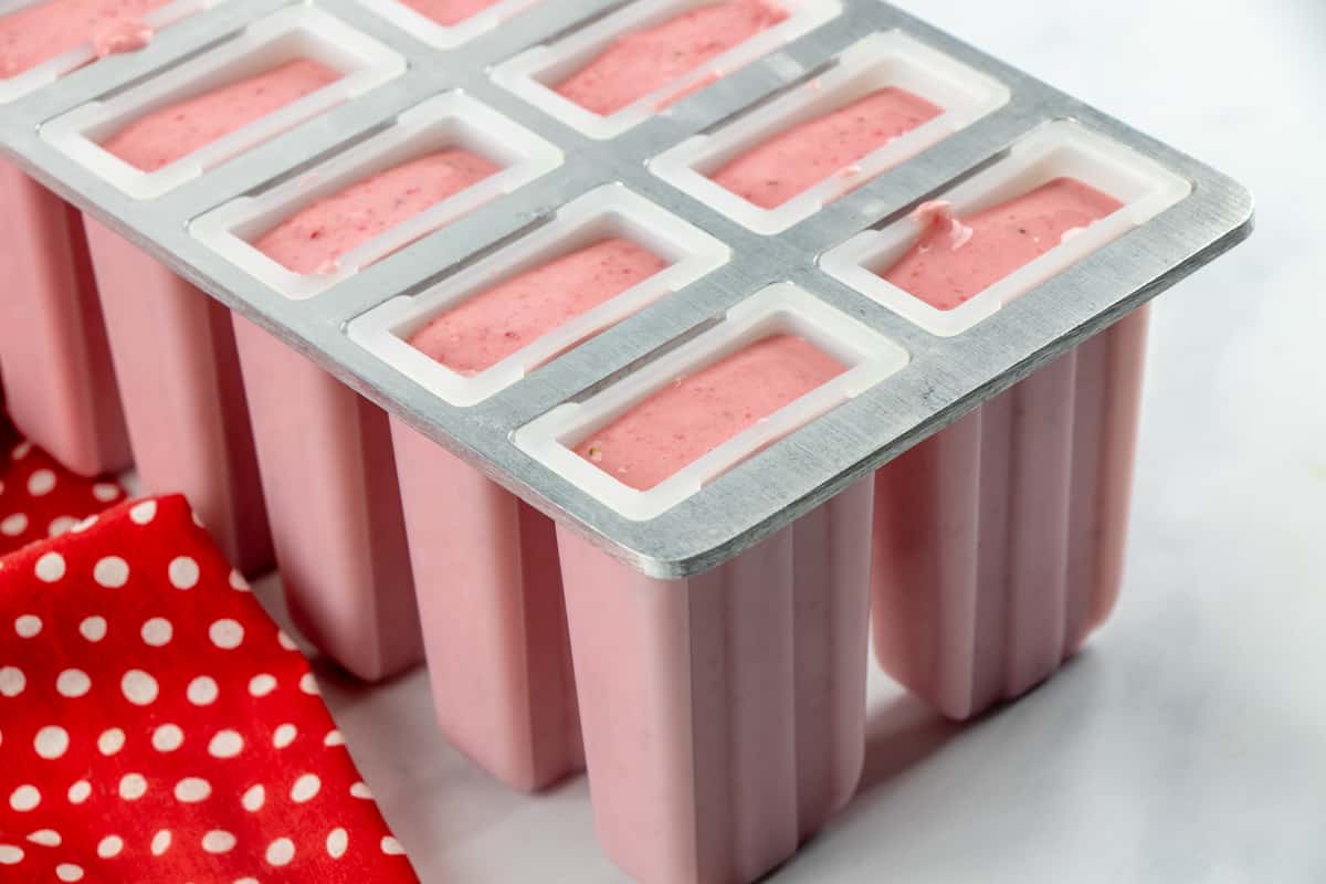 strawberry yogurt mixture in plastic popsicle molds.
