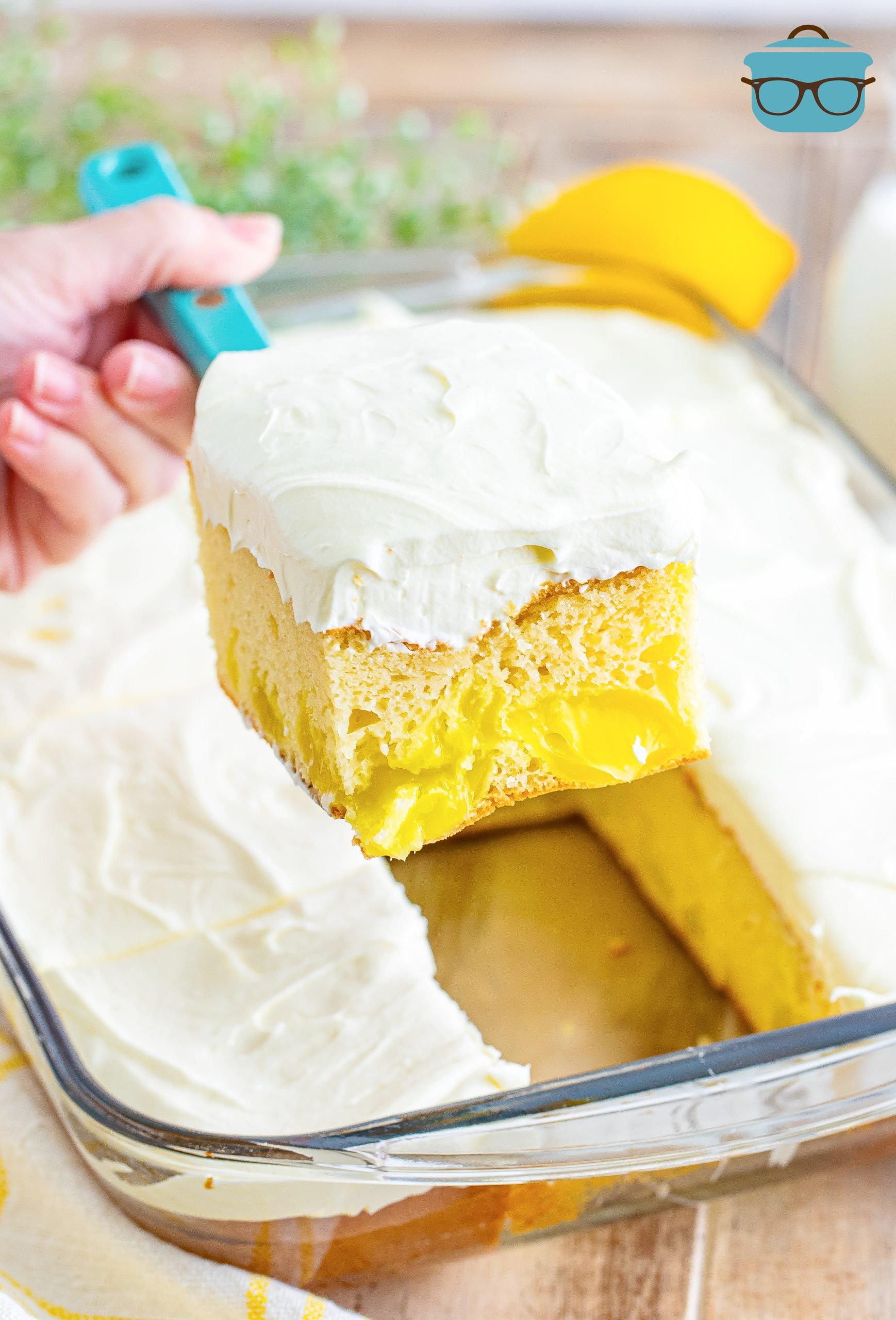 A slice of Lemon Dream Cake being removed from the baking dish with the rest of the cake.