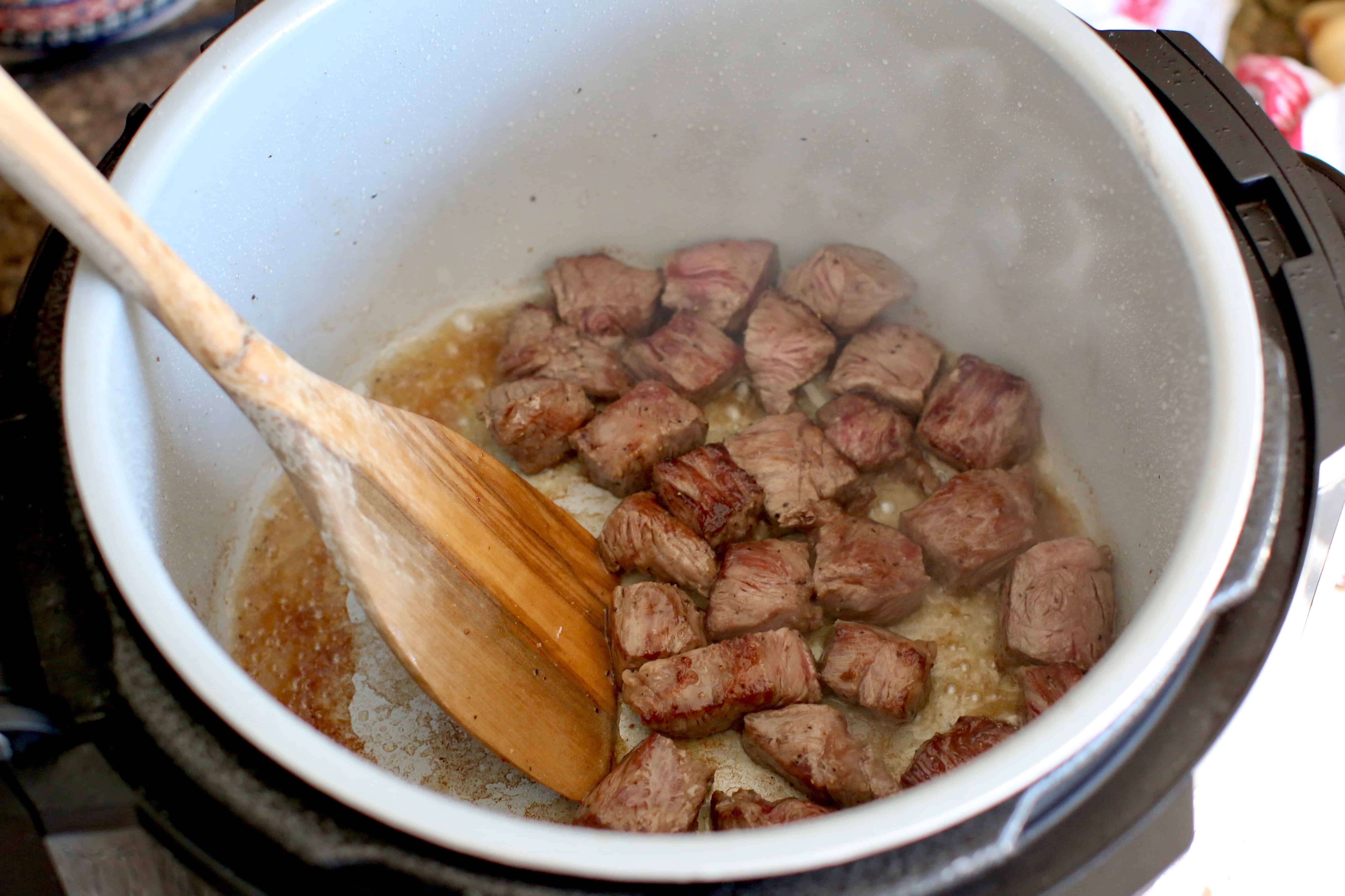 browning meat in olive oil in the bottom of an Instant Pot