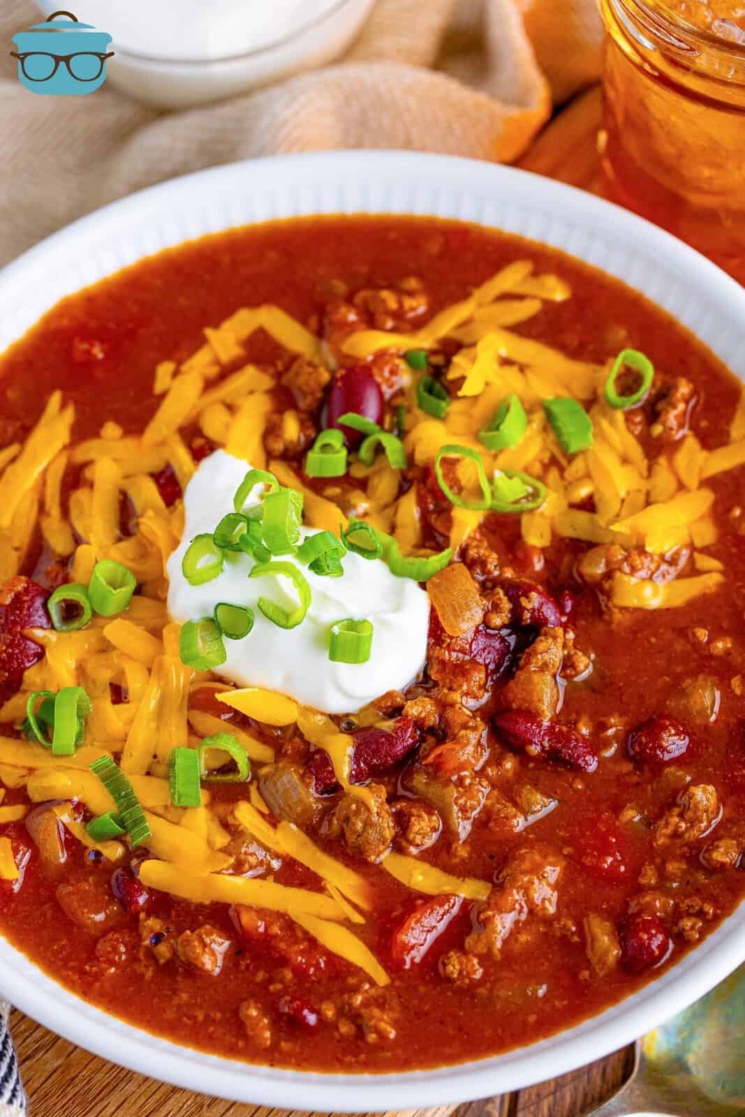 an overhead photo of a bowl of chili topped with cheese and sour cream. 