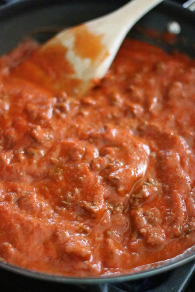 stirring jarred spaghetti sauce into cooked ground beef in large skillet