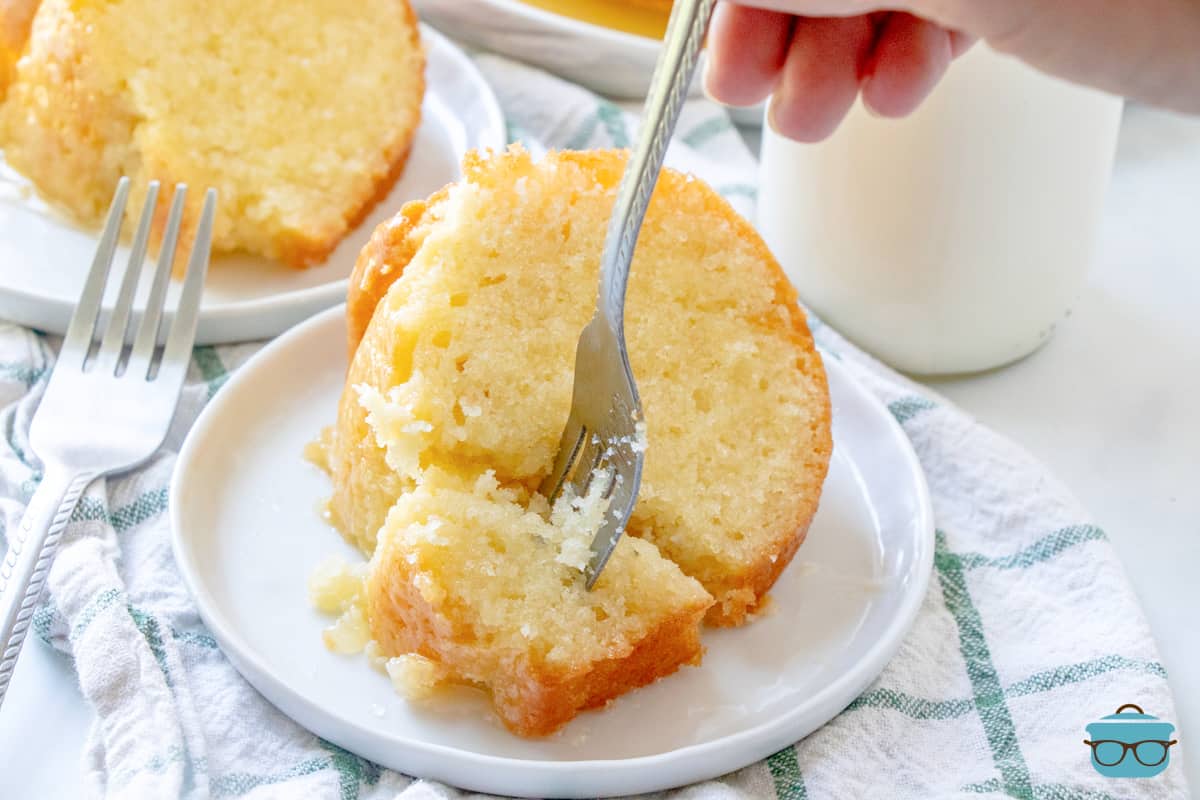 slice of butter cake on a small round white plate with a fork shown inserted into the cake.