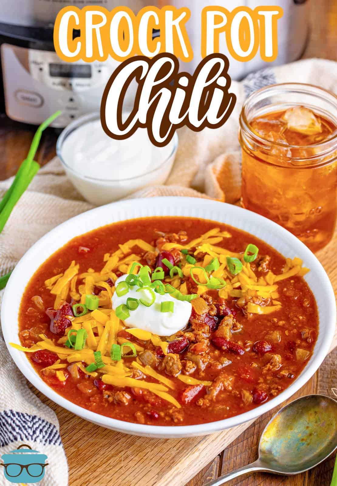 a white bowl of chili with a mason jar of sweet tea and a slow cooker in the background.
