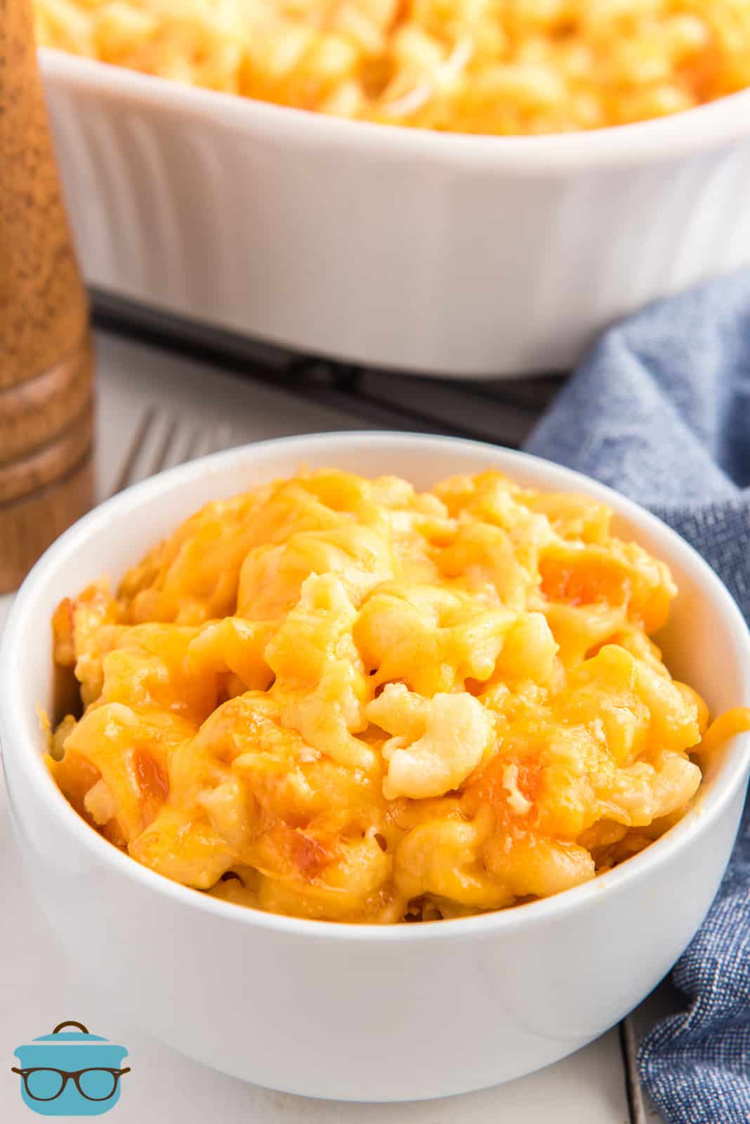 A small white bowl of macaroni and cheese in front of baking dish.