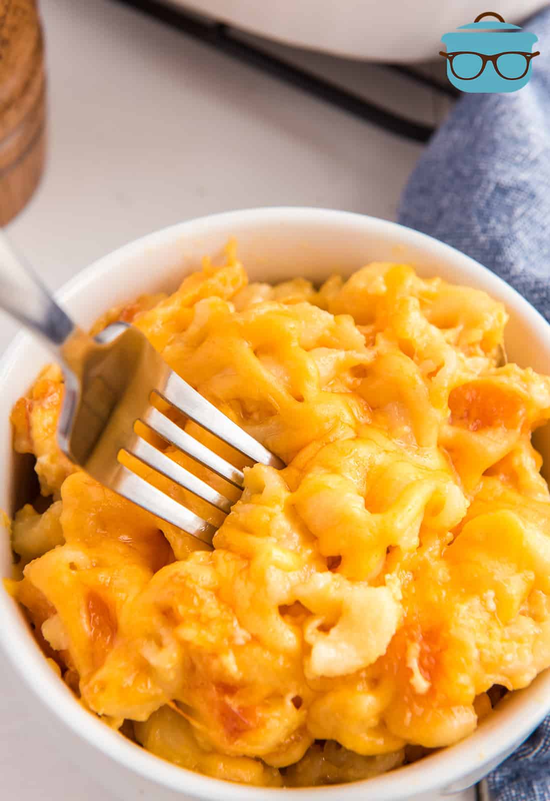 a fork poking into a bowlful of macaroni and cheese.