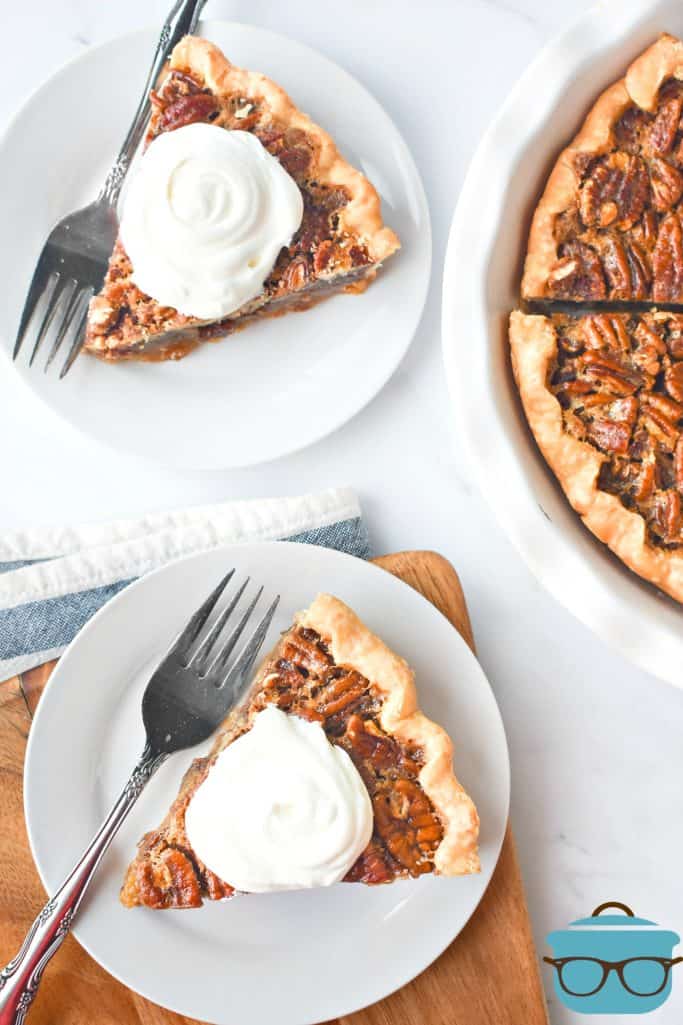 Two slices of pecan pie on white plates with forks