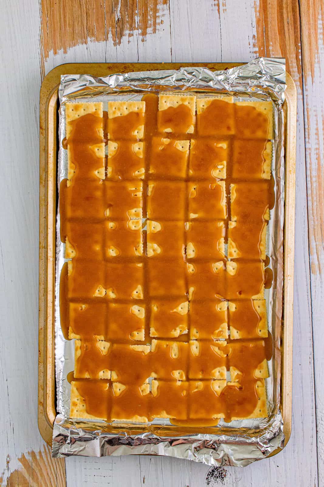 brown sugar butter mixture poured into crackers on a baking sheet. 