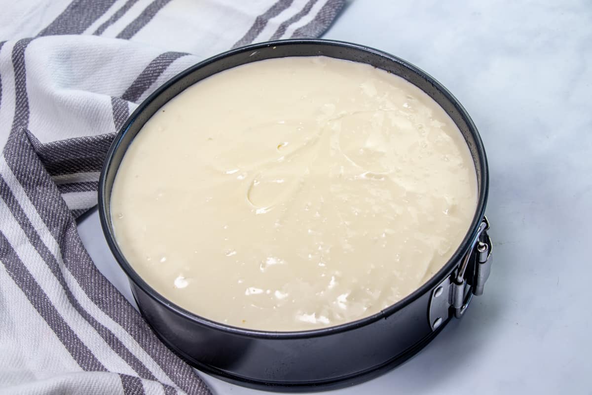 cheesecake batter poured into prepared graham cracker crust in a springform pan.