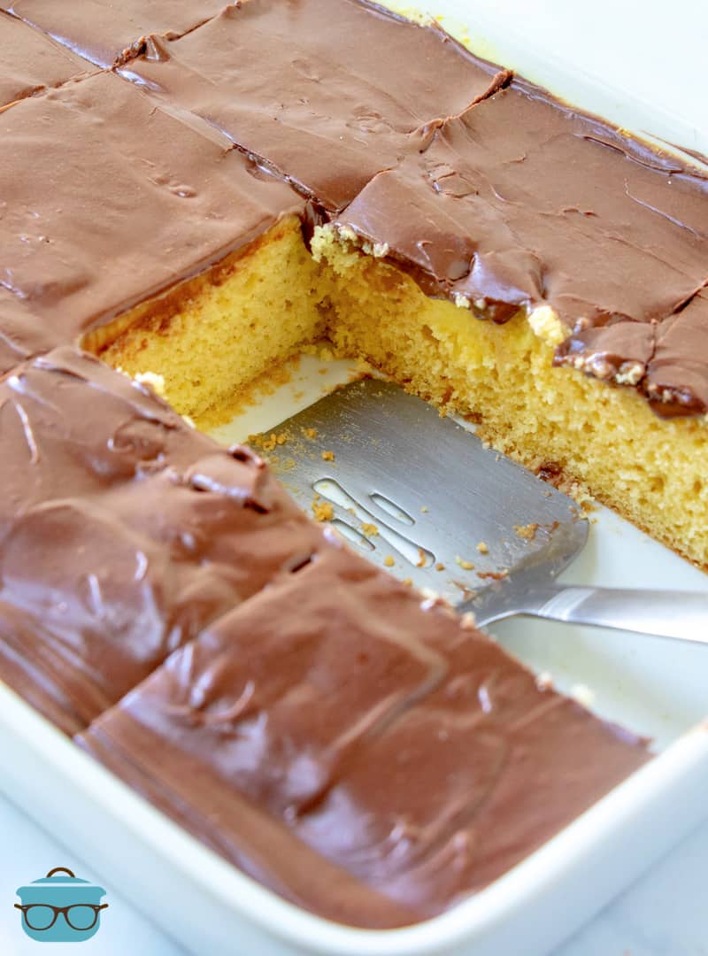 Boston cream poke cake in a metal baking dish with two slices removed. 