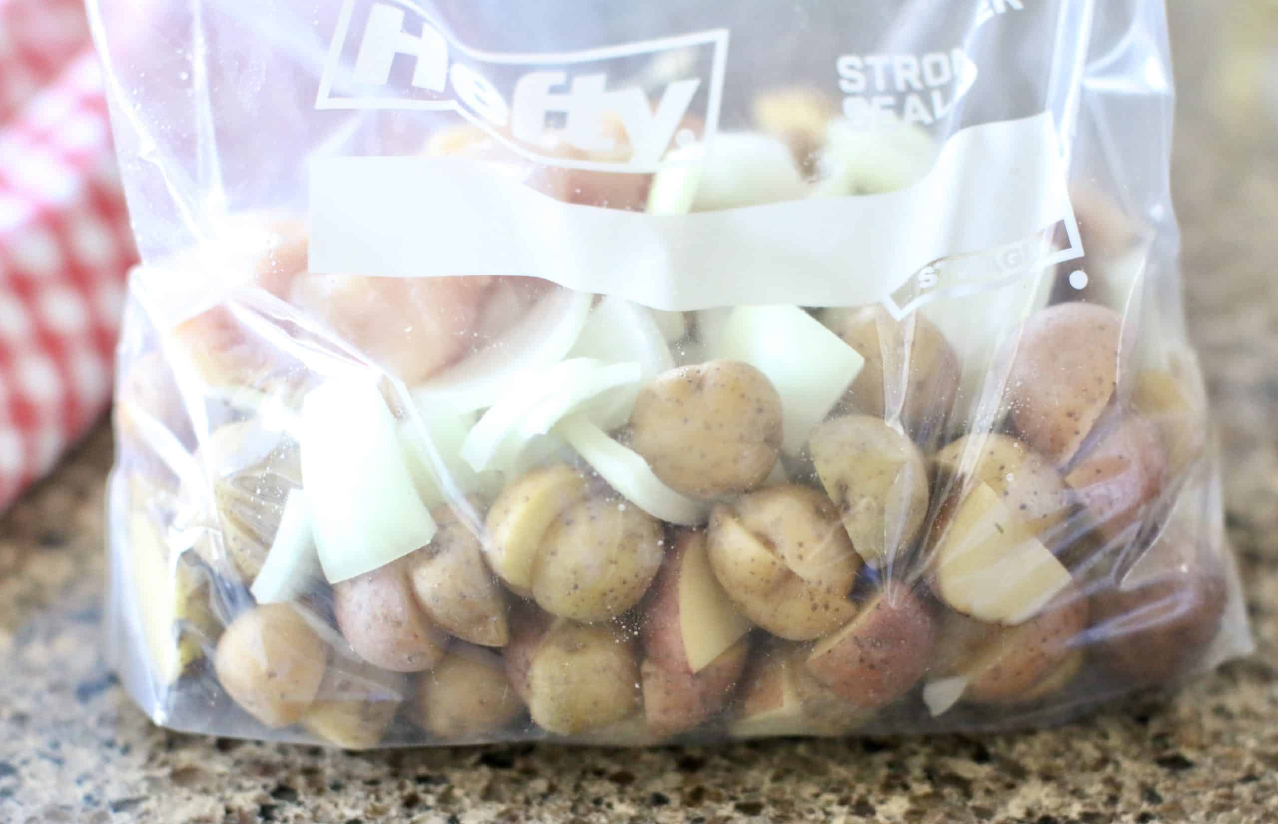 large zip top plastic bag full of potatoes, chicken and onions and seasonings mixed together.