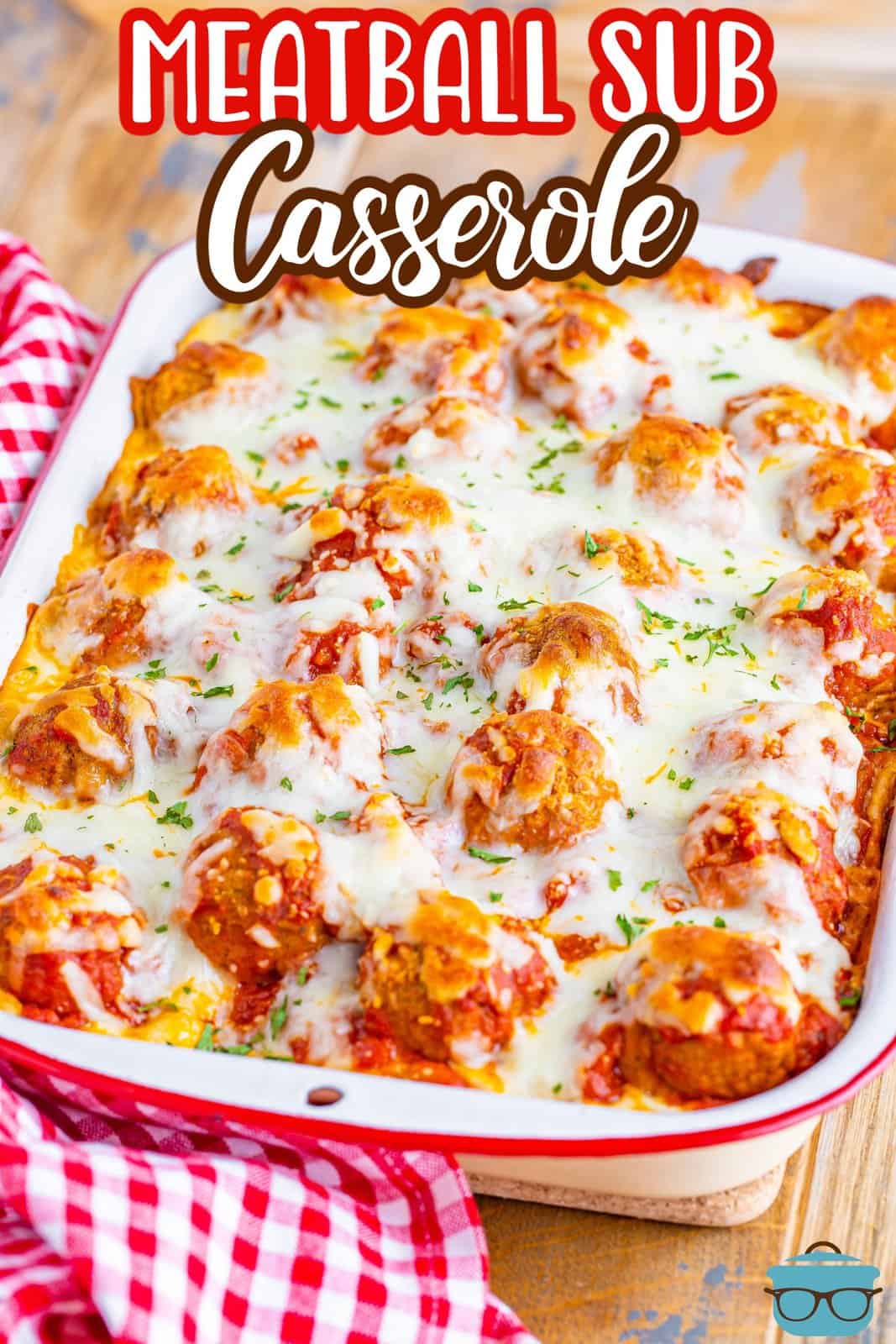 Meatball Sub Casserole shown fully baked in a white and red casserole dish with a red and white dishcloth on the side.