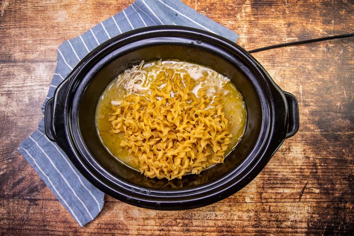egg noodles added to the slow cooker after chicken has been cooked and shredded.